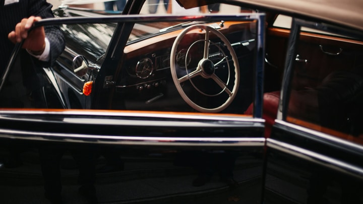 Chauffeur opening the door of a black executive car